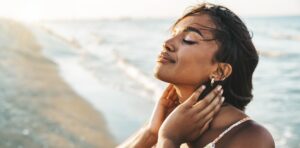 Peaceful black woman enjoying sun light at the beach