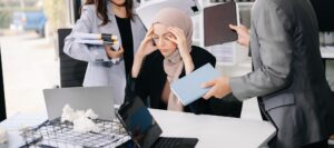 Stressed Asian Businesswoman Surrounded by Overwhelming Paperwork Concept of Workplace Anxiety