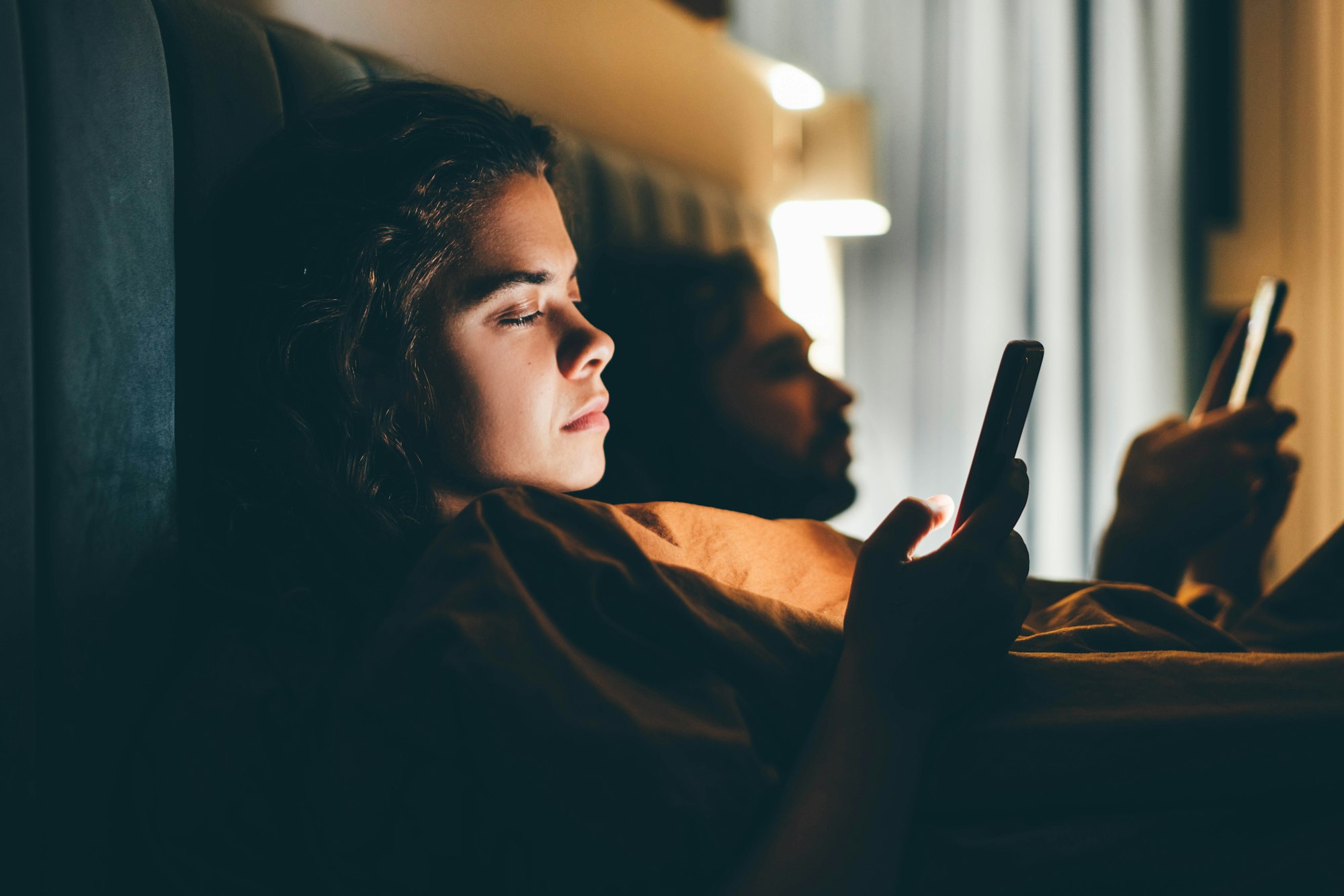 Couple with smartphones in their bed. Mobile phone addiction.