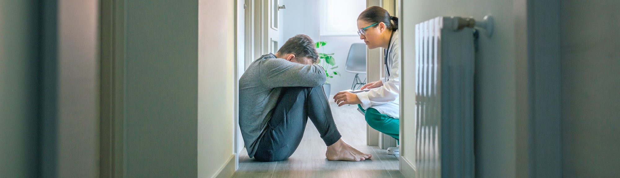 Psychiatrist talking to patient with mental disorder and suicidal thoughts sitting on room floor