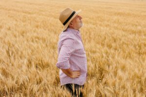 Satisfied farmer in a hat looking away at his thriving crop in the golden sunset