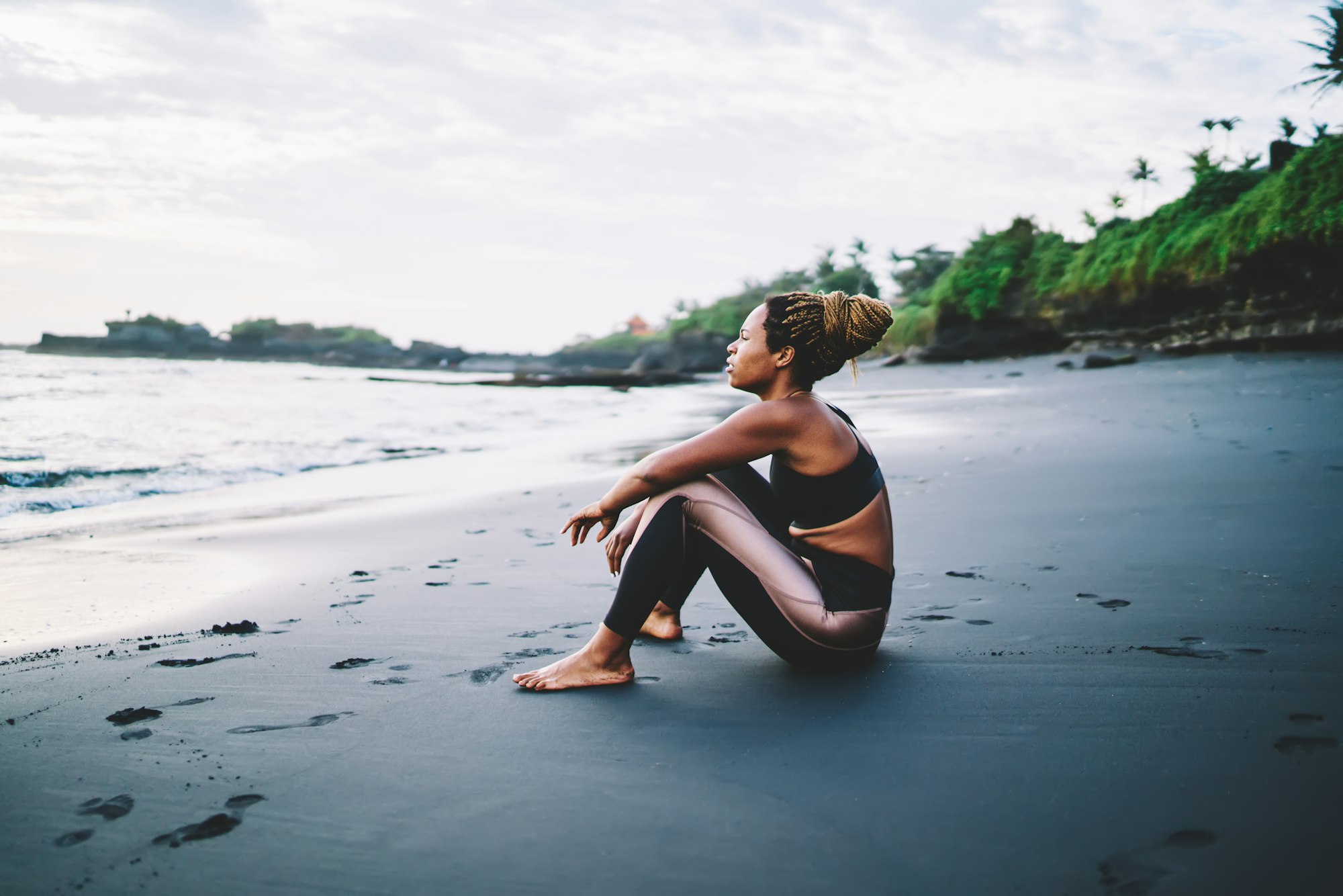 Casual woman in tracksuit keeping healthy lifestyle getting energy on workout near sea