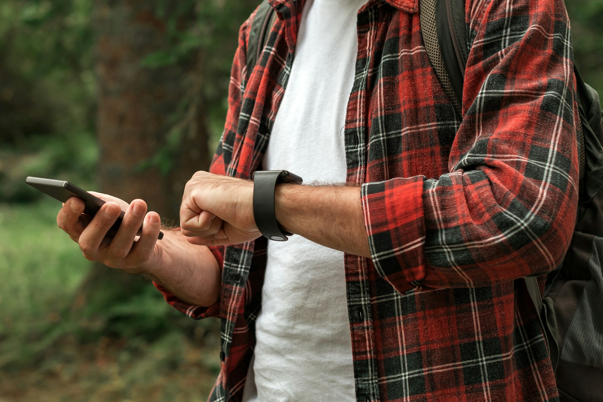 Hiker connecting smartwatch to smartphone to synchronize the data