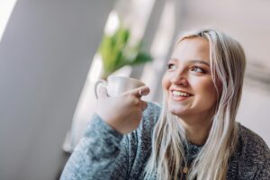 Positive woman holding cup in office