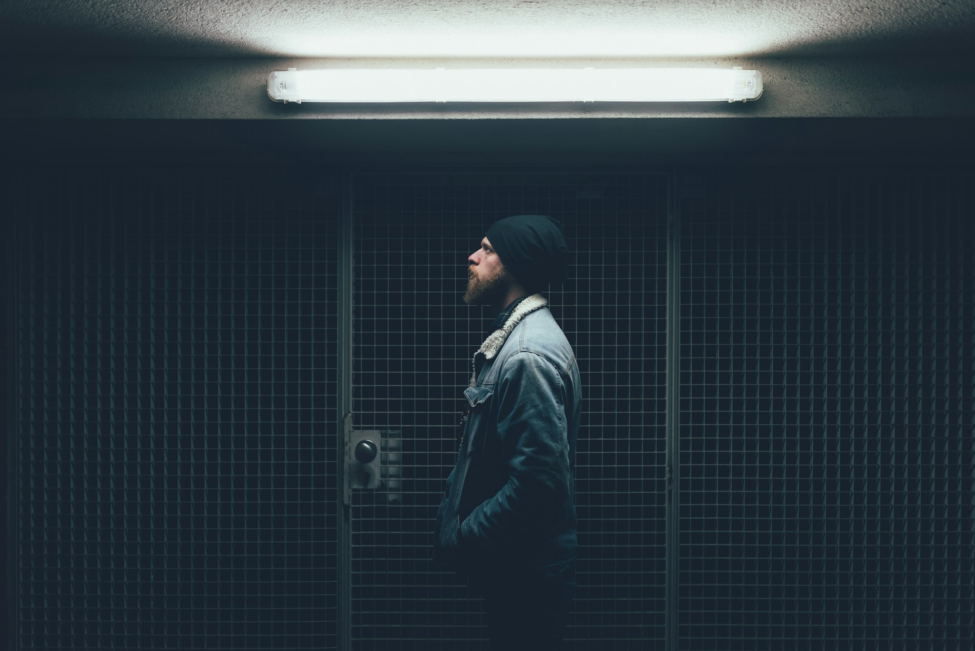 Young male hipster in dark city doorway at night