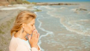 Beautiful woman prays on the sea shore