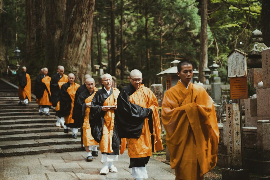 Monks in traditional orange robes on a forested path