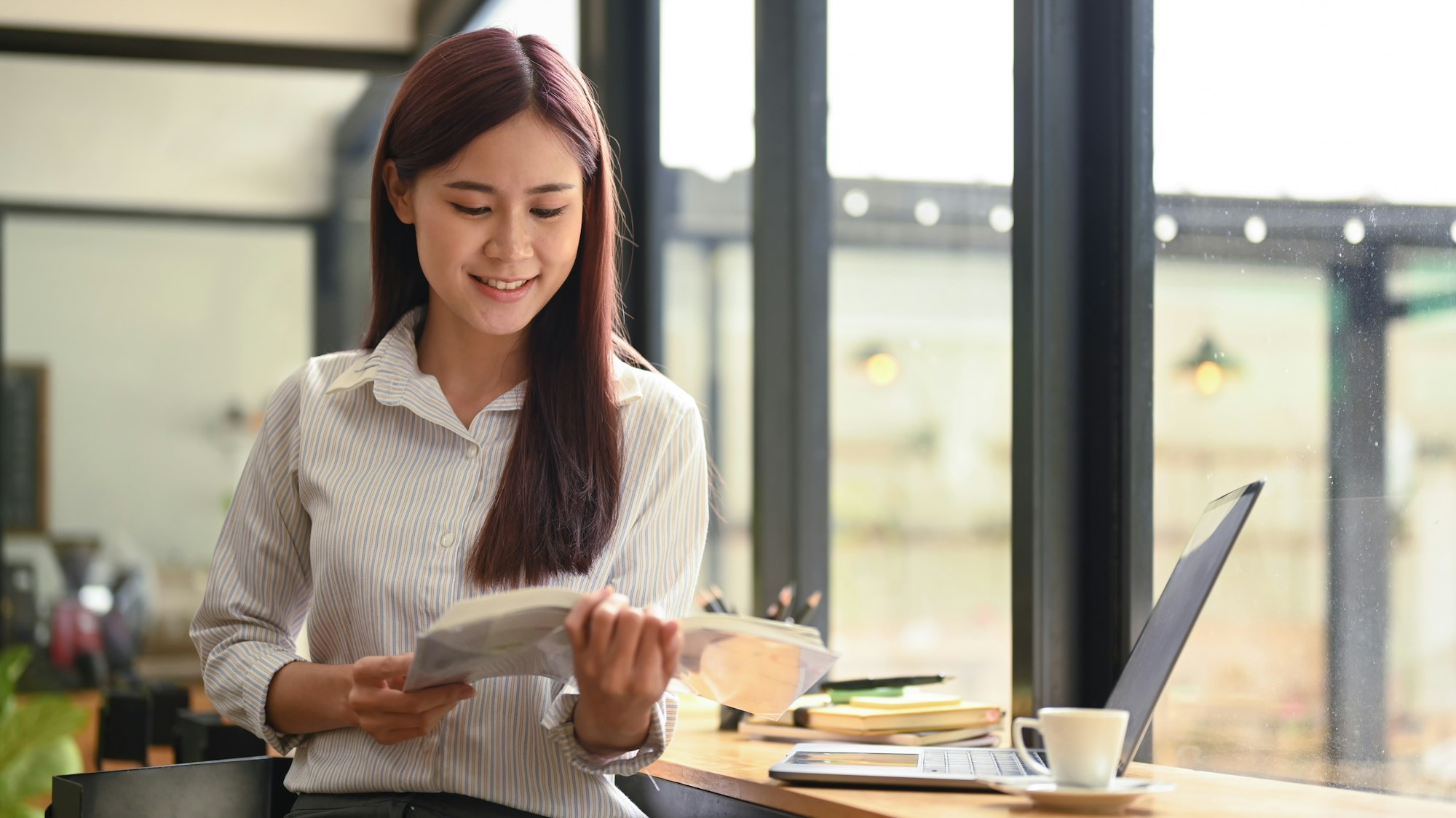 Calm asian woman sitting in coffee shop and reading book.