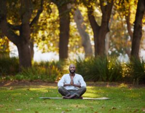 Full length shot of a handsome young man meditating while practicing yoga outside at the park