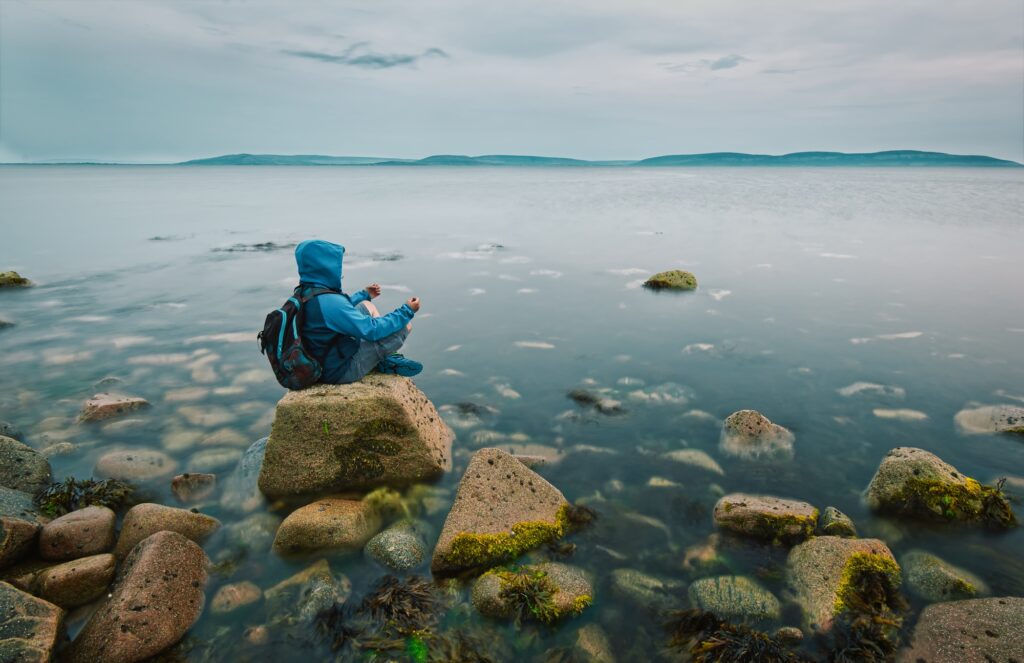 Man meditating on the rock in the ocean